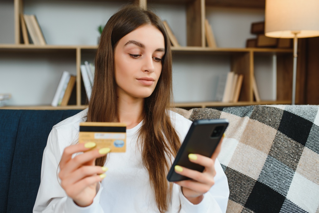 happy-young-woman-holding-phone-credit-card-sitting-couch-online-shopping.jpg диван